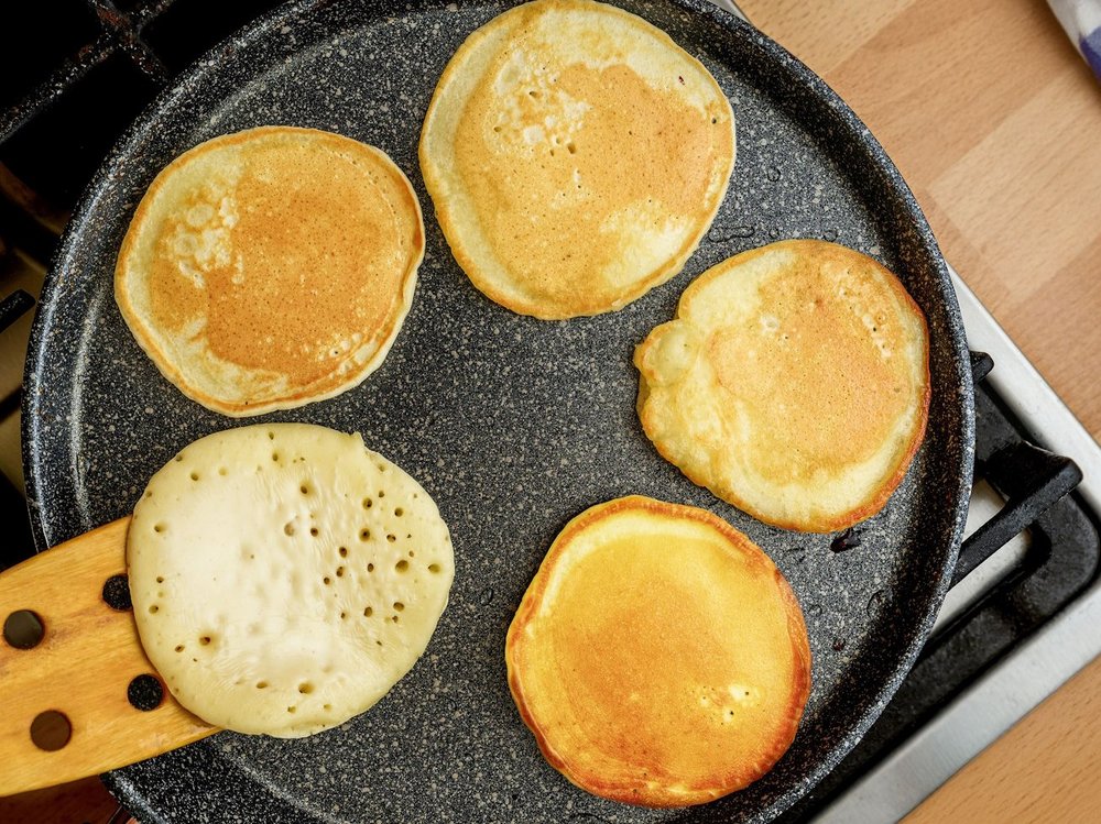 In einer schwarzen Pfanne liegen fünf kleine Pfannkuchen.