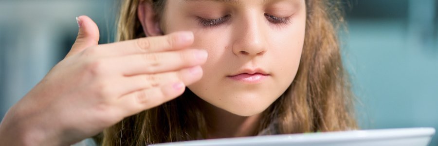 Maedchen schnuppert mit geschlossenen Augen an einem Teller mit Essen.