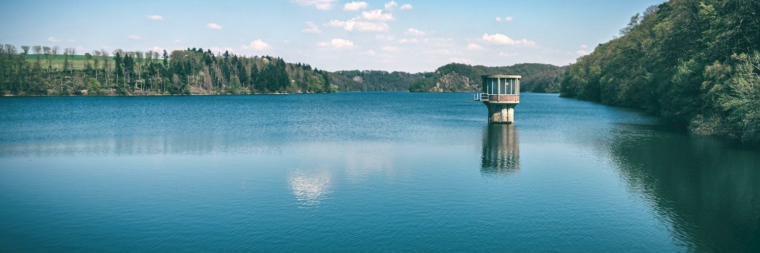 Eine große Talsperre mit dem Entnahmeturm für Trinkwasser rechts.