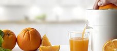 and presst Orangenhälfte auf Presse und Orangensaft läuft ins Glas