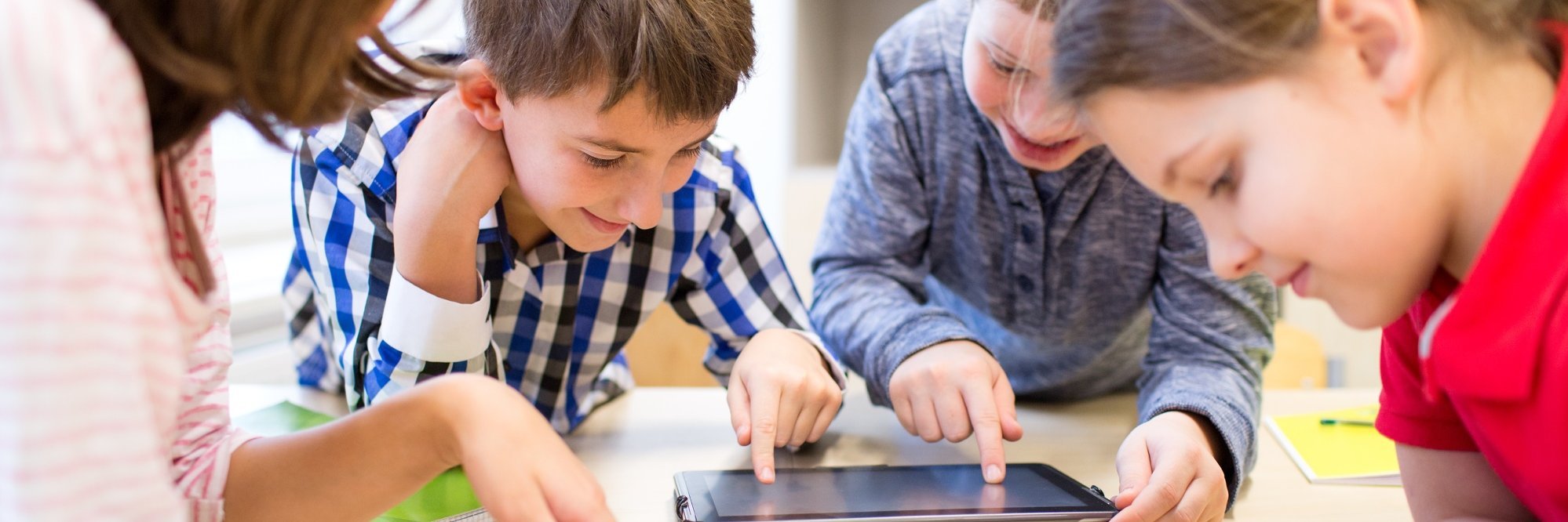 Mehrere Schülerinnen und Schüler beugen sich über drei Tablets.