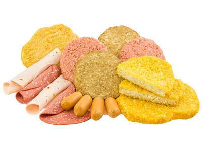 Aufgerollte Scheiben Fleisch-Ersatz, vegane und vegetarische Burger-Scheiben und Würstchen sind abgebildet.