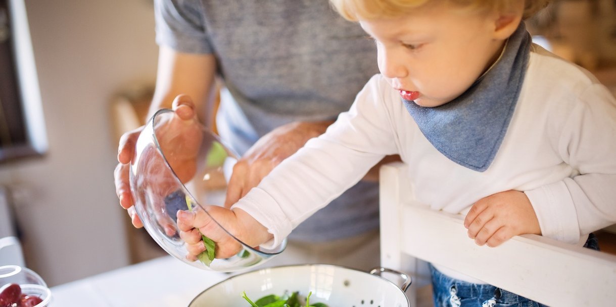 Kleinkind füllt Spinatblätter in ein Abtropfsieb.. Artikel "Den Essalltag mit Kindern gestalten" öffnen.