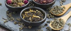 Verschiedene lose Teesorten in Schälchen und Holzlöffeln
