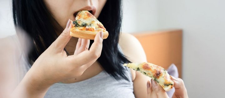 Frau hält jeweils ein Pizzastück in den Händen