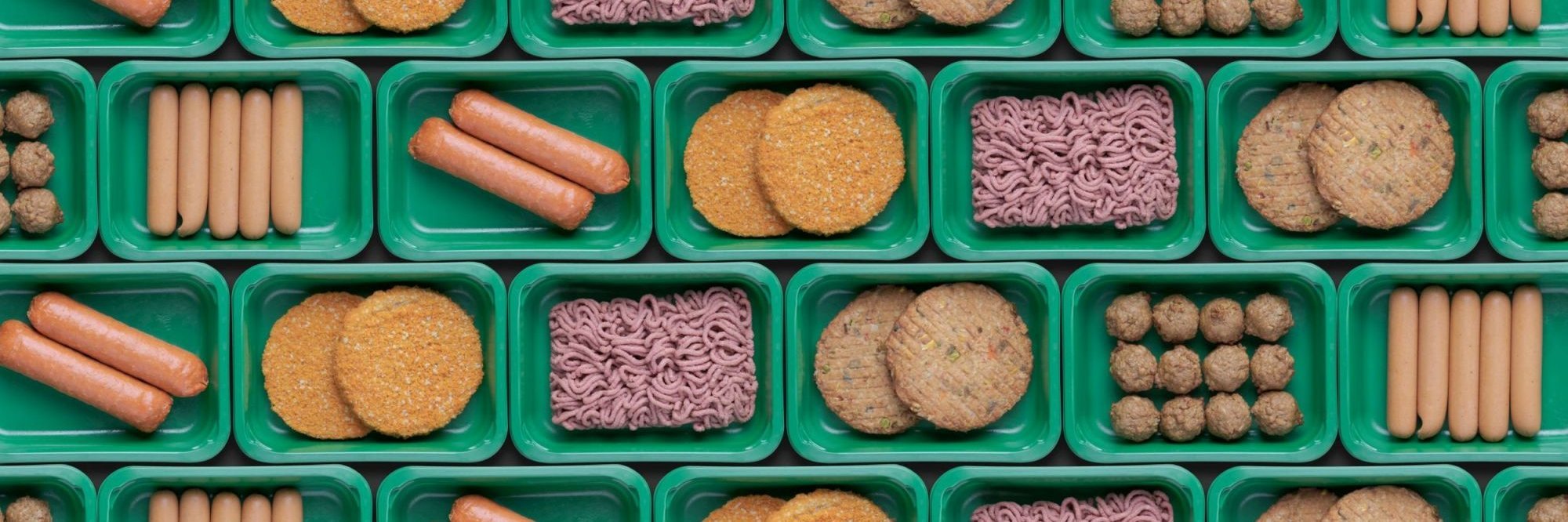 Verschiedene Fleischalternativen in grünen Plastikschalen.