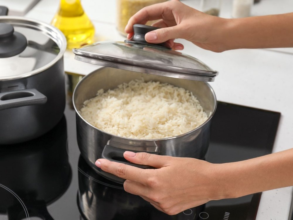 Frau hält einen Topf mit gekochtem Reis.