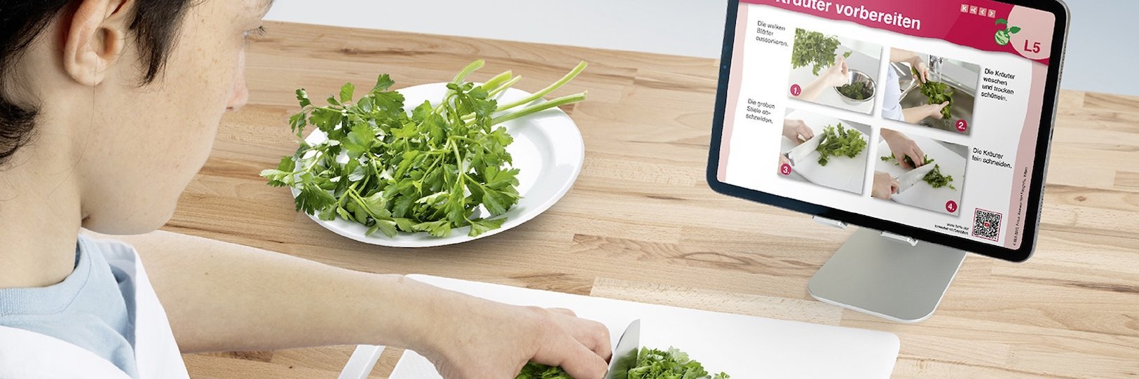 Ein Junge schnippelt Petersilie vor einem Tablet.