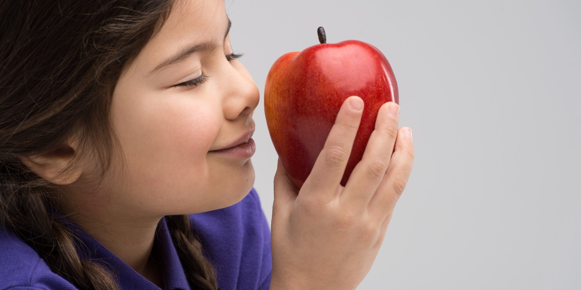 Ein Mädchen riecht an einem Apfel.. Artikel "Schmecken mit allen Sinnen" öffnen.