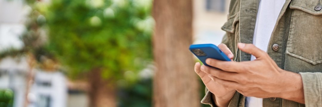 Ein junger Mann schaut auf ein Smartphone in seiner Hand.