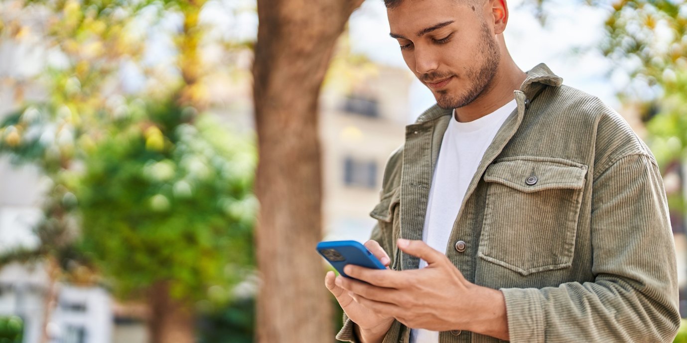 Ein junger Mann schaut auf ein Smartphone in seiner Hand.. Artikel "Wie informiere ich mich über Nahrungsergänzungsmittel?" öffnen.