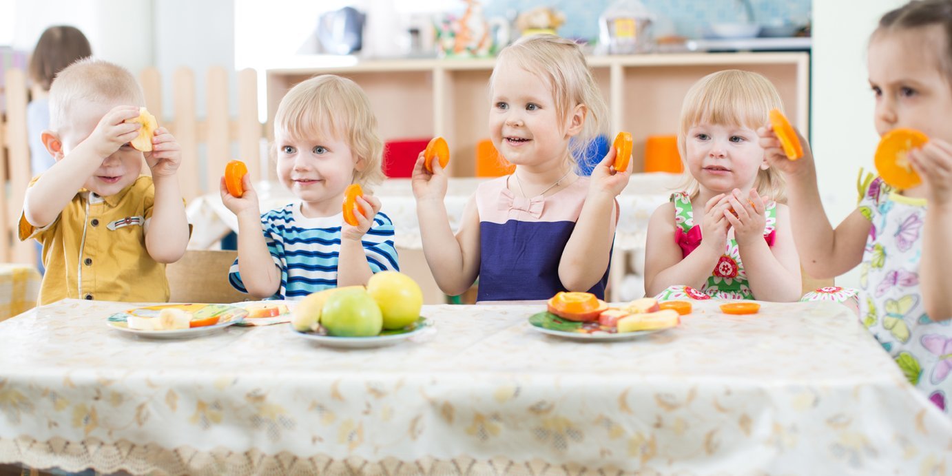 Kitakinder Sitzen an einem kleinen Tisch mit Tischdecke und essen geschnittenes Gemüse.. Artikel "Schmecken mit allen Sinnen" öffnen.