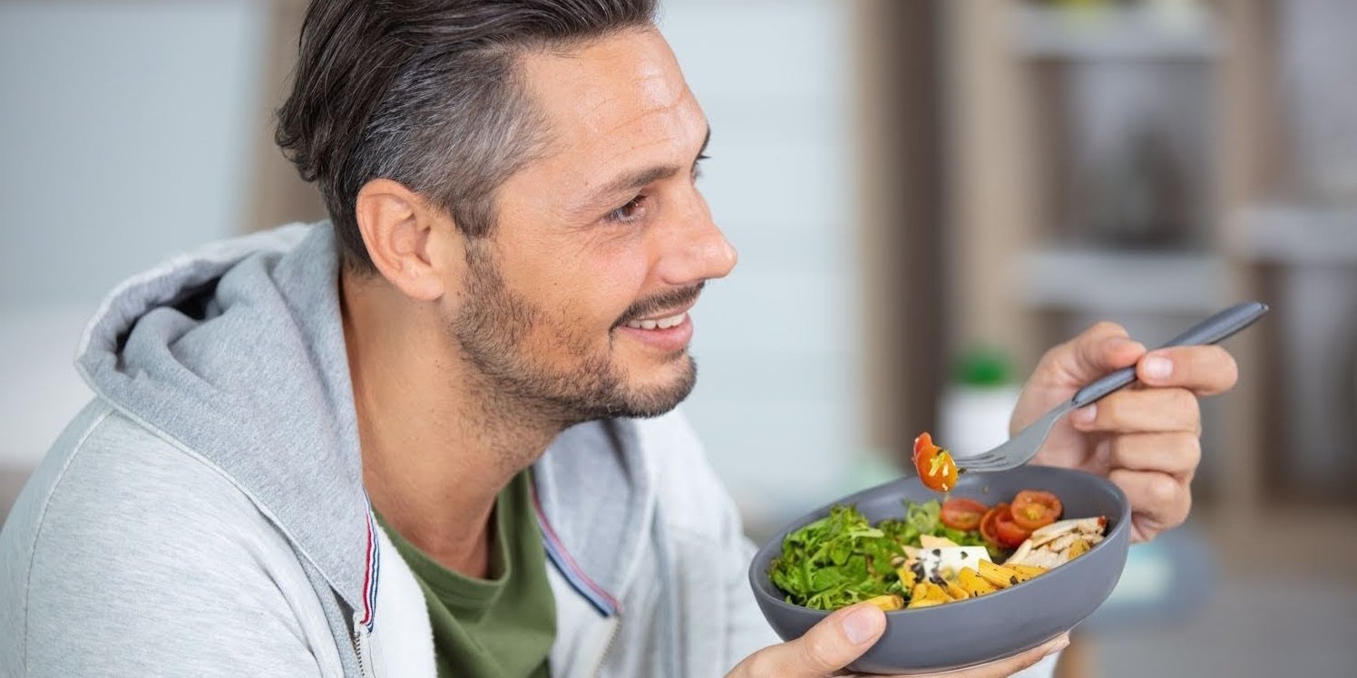 Ein Mann hält eine Schüssel mit gesundem Essen und eine Gabel.. Artikel "Essen" öffnen.