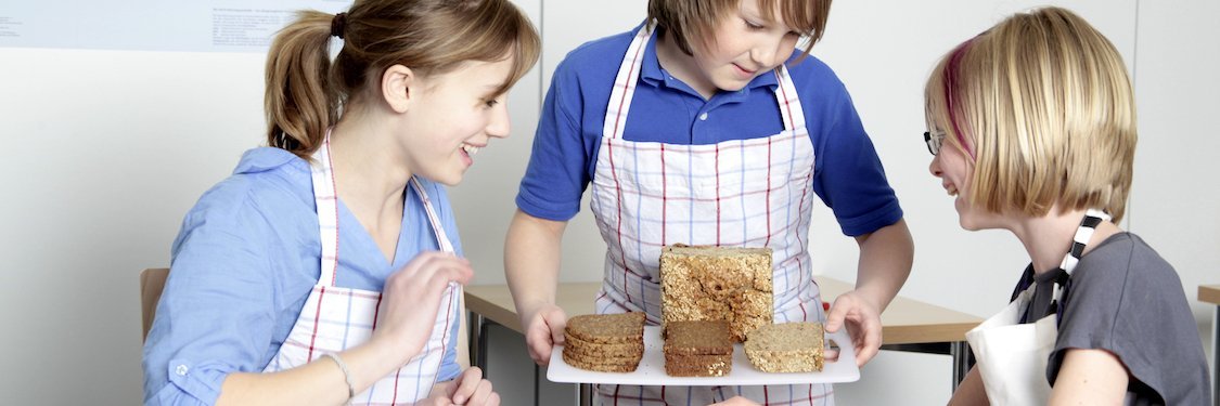 Drei Jungendliche bereiten im Klassenzimmer eine Brotverkostung vor.