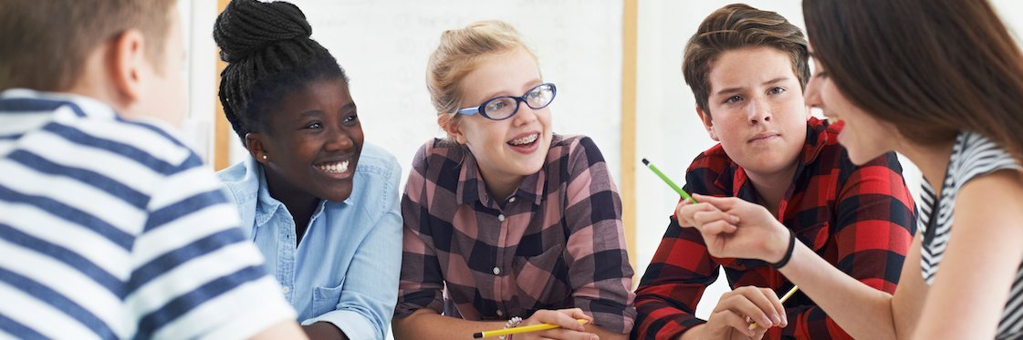 Fünf Schülerinnen und Schüler der Sekundarstufe sitzen an einem Tisch.