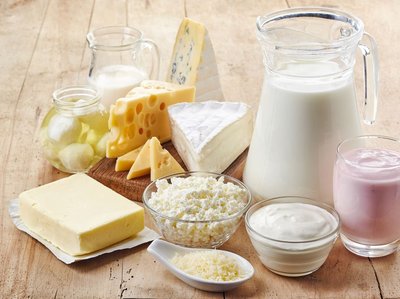 Es sind verschiedene Milchprodukte abgebildet: Milch, Butter, Käse, Joghurt, Hüttenkäse.