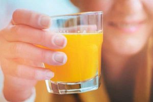 Junge Frau hält Glas mit Orangensaft in der Hand
