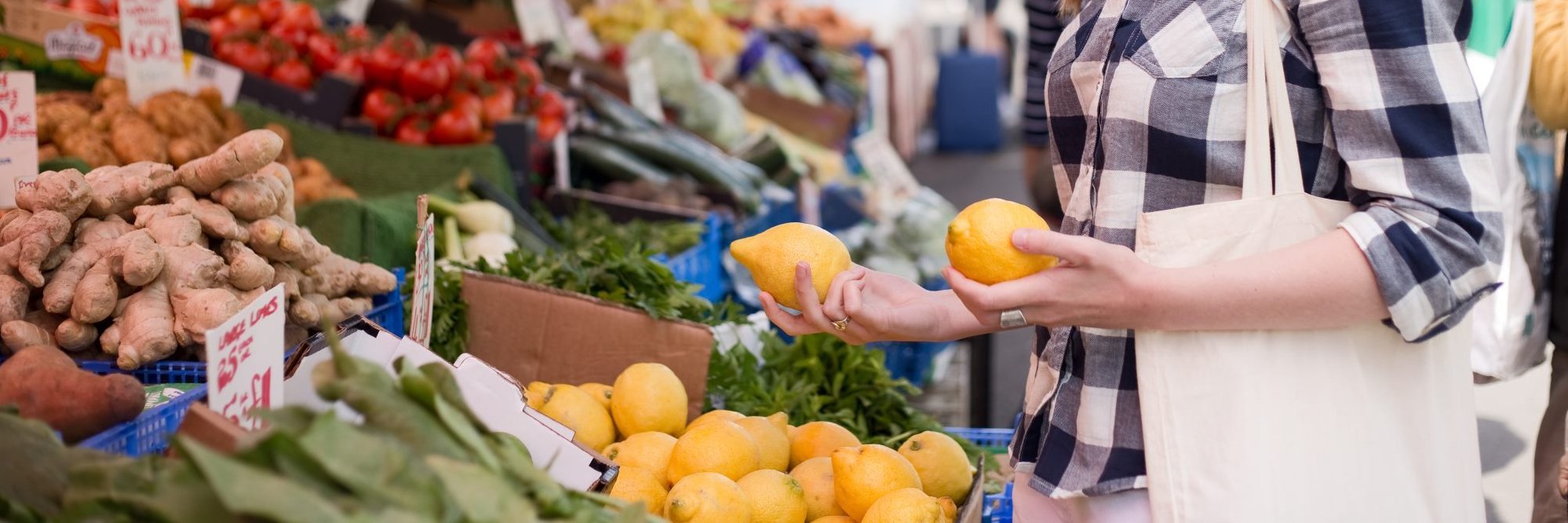 Eine Frau schaut sich an einem Marktstand Zitronen an.