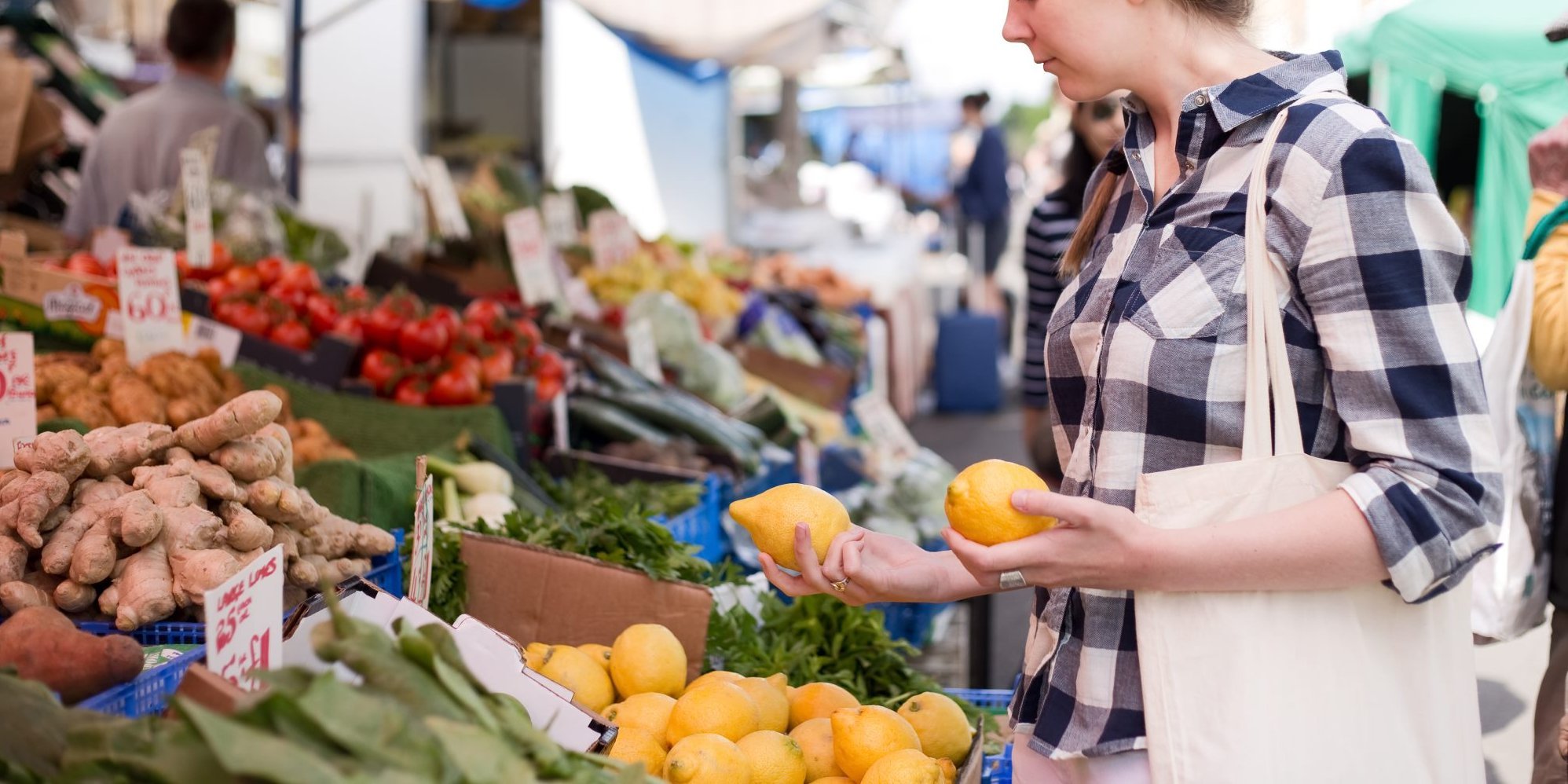 Eine Frau schaut sich an einem Marktstand Zitronen an.. Artikel "Nachhaltiger einkaufen – was geht?" öffnen.