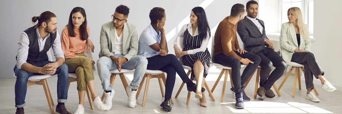 Junge Leute sitzen in einer Reihe auf Stühlen.