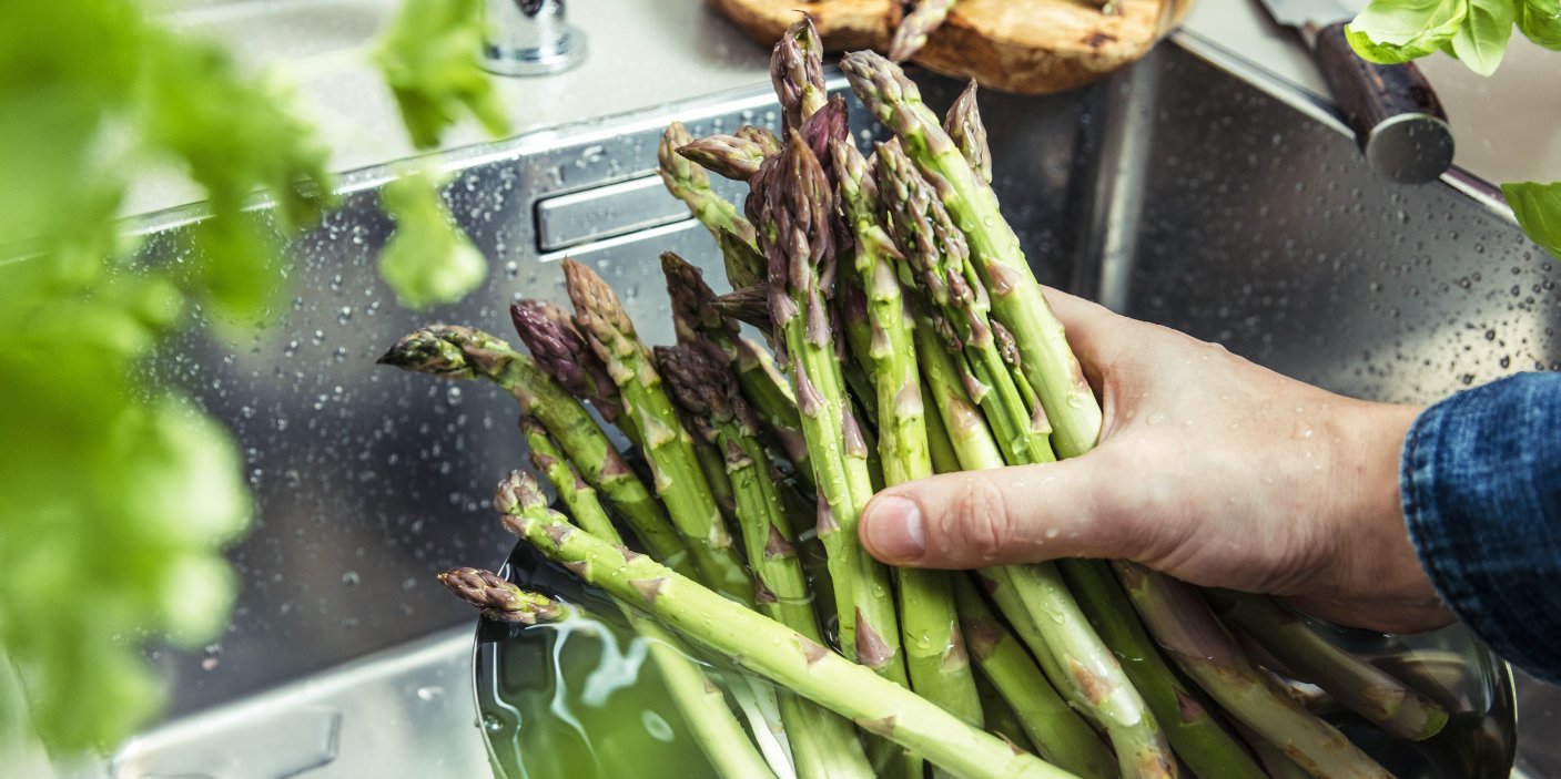 Hand wäscht grünen Spargel im Waschbecken.. Artikel "Spargel: Vom Einkauf in die Küche" öffnen.