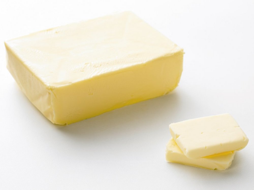 Großes Stücl Butter mit zwei kleinen Stücken davor.