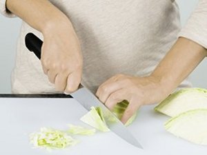 eine Person schneidet den Weißkohl in Streifen.