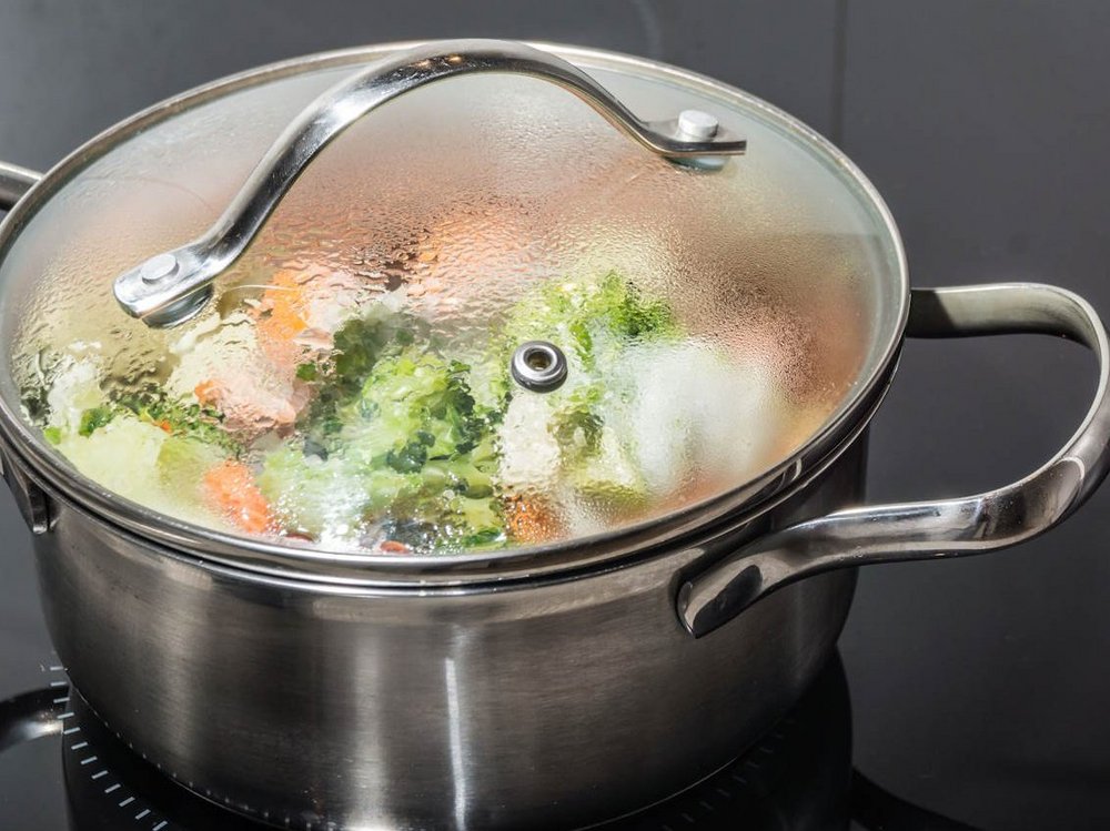 In einem Edelstahltopf mit Glasdeckel befindet sich buntes Gemüse.