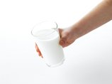 Eine Hand hält ein Glas Milch.