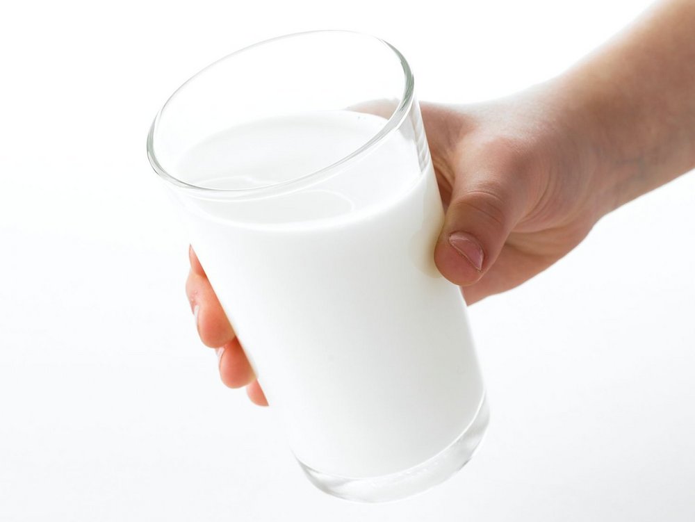 Eine Hand hält ein Glas Milch.