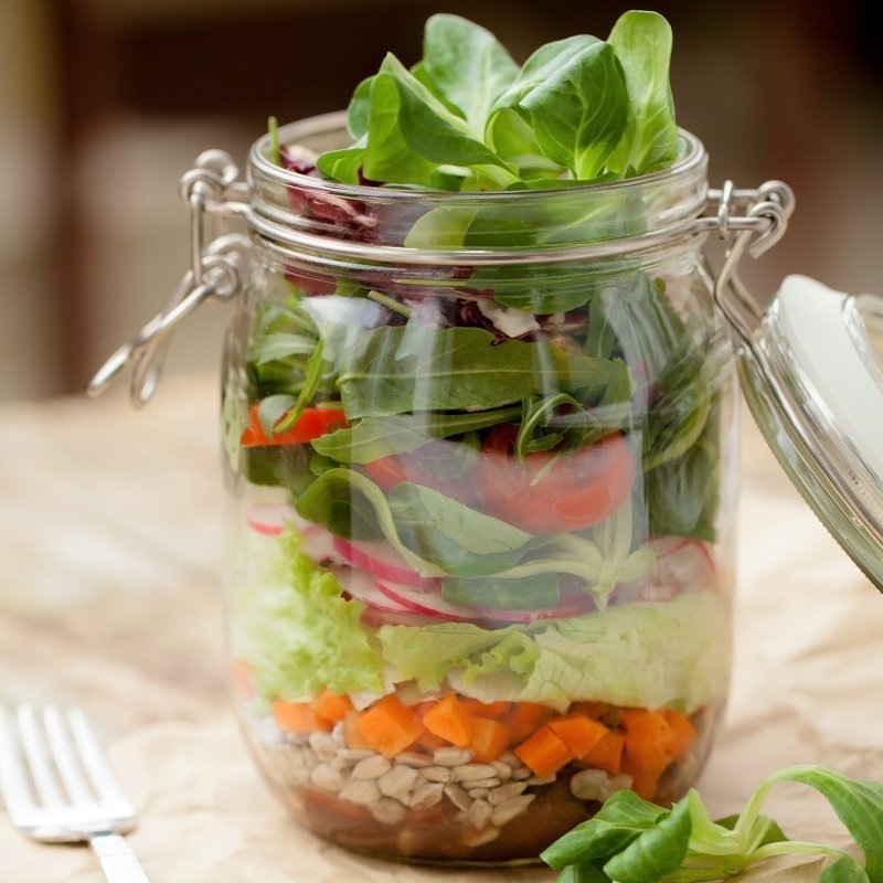 Zutaten für einen Salat sind in einem Einmachglas geschichtet.