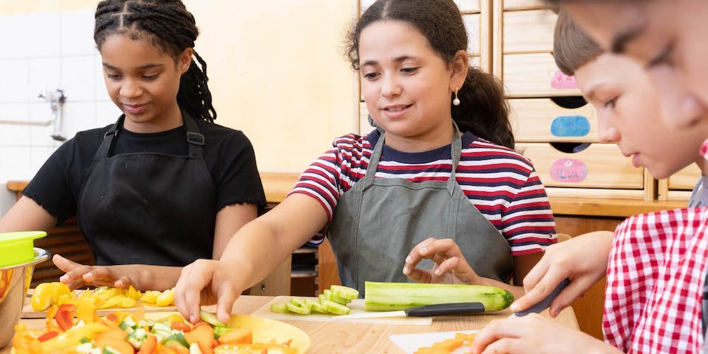 Schülerinnen und Schüler schnippeln im Klassenzimmer Gemüse.. Artikel "Der Ernährungsführerschein" öffnen.