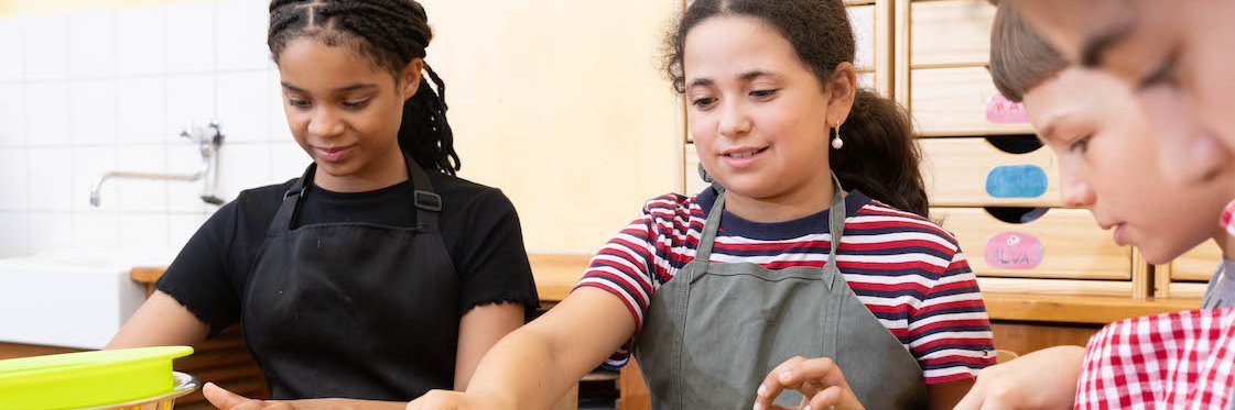 Schülerinnen und Schüler schnippeln im Klassenzimmer Gemüse.