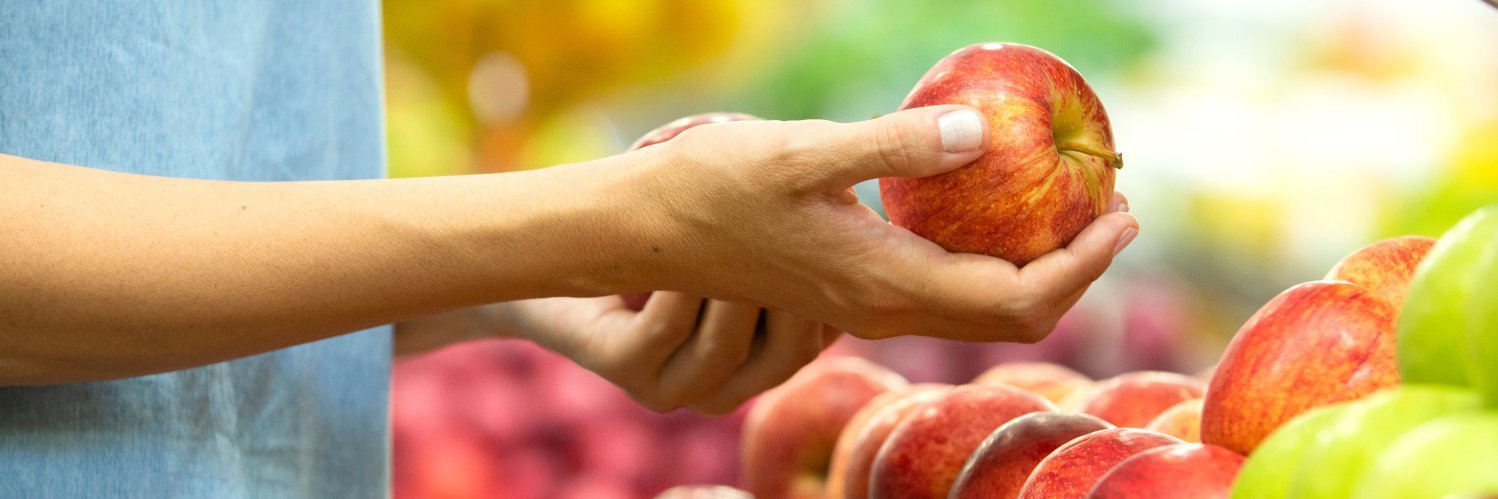 Frau am Apfelstand hält in der Hand einen Apfel.