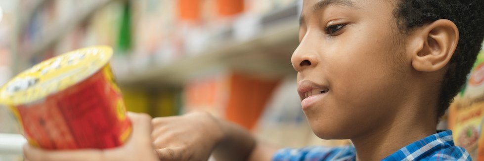 Junge schaut sich im Supermarkt ein Lebensmitteletikett an.