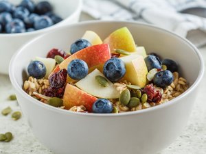 In einer weißen Schüssel befindet sich Müsli mit Obst als Topping.