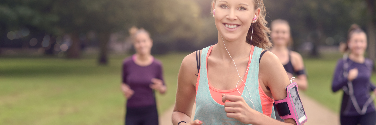 Eine Gruppe von jungen Frauen joggt durch einen Park.