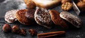 Lebkuchen liegen in einer Reihe und davor liegen Zimtstangen und Nelken