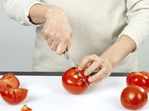 eine Person schneidet eine Tomate.