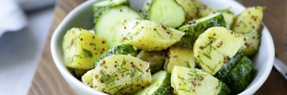 Kartoffelsalat mit Salatgurke in einer Schüssel.
