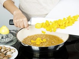 eine Person gibt Mangowürfel in Pfanne.