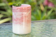 Rosa von pürierten Himbeeren durchzogener Naturjoghurt in einem Glas.
