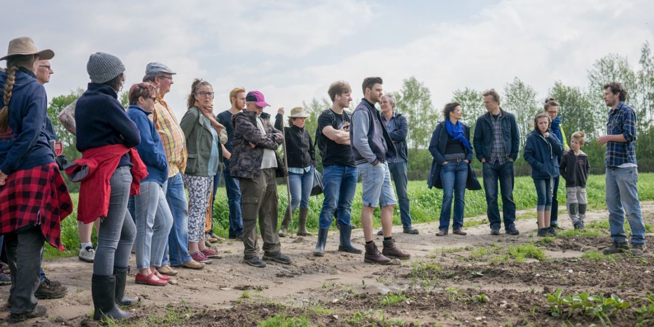 Solawi-Mitglieder und ein Gärtner stehen auf einem Feld.. Artikel "Solidarische Landwirtschaft " öffnen.