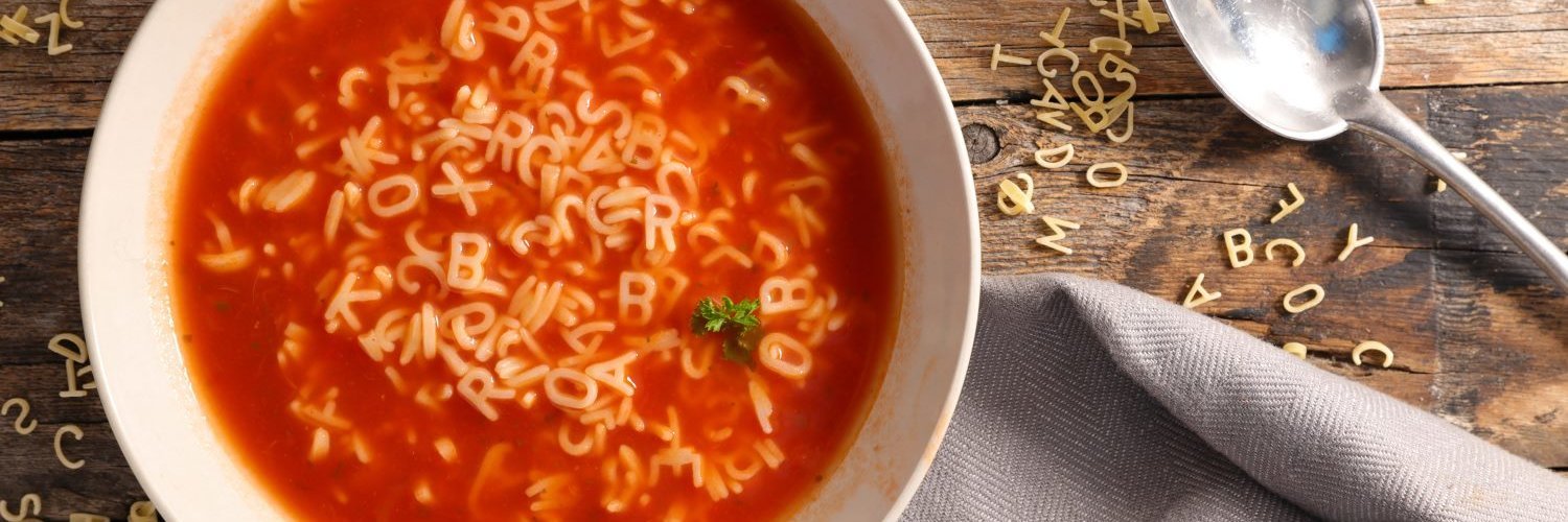 Auf einem Teller befindet sich eine Tomatensuppe mit Buchstabennuden.