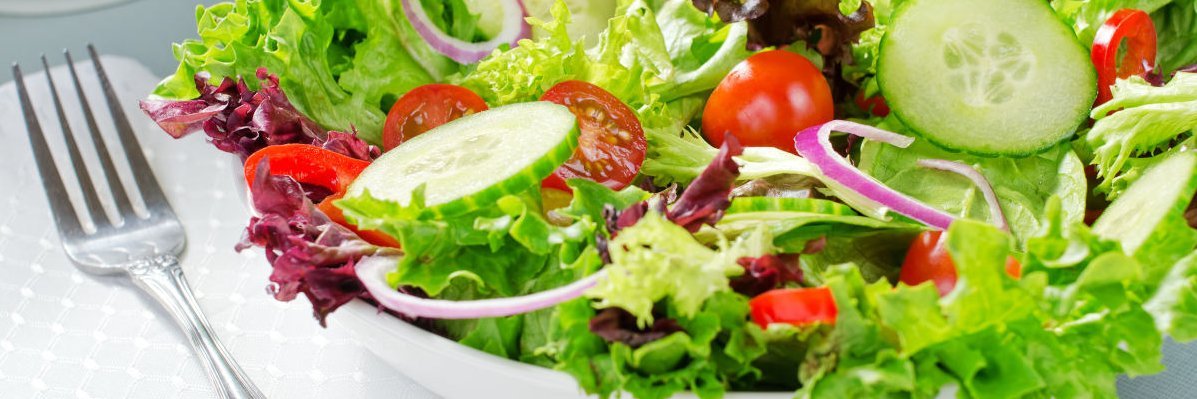 Neben einer Schüssel mit buntem Salat liegt eine Gabel.