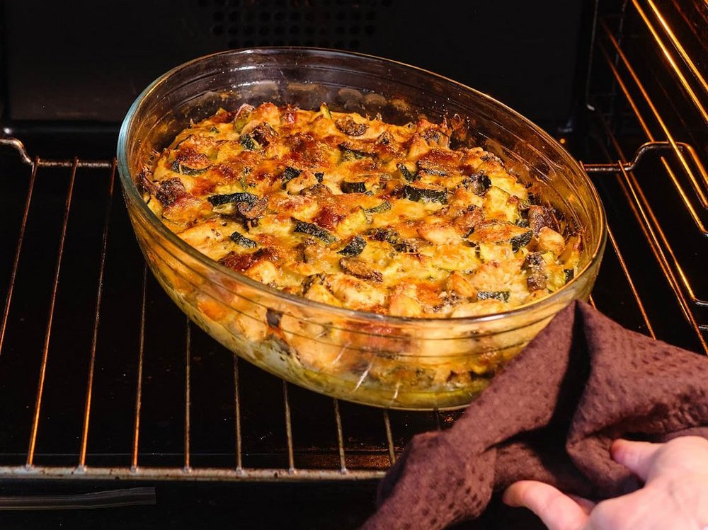 In einem geöffneten Backofen steht eine Glasschüssel mit einem fertigen Auflauf.