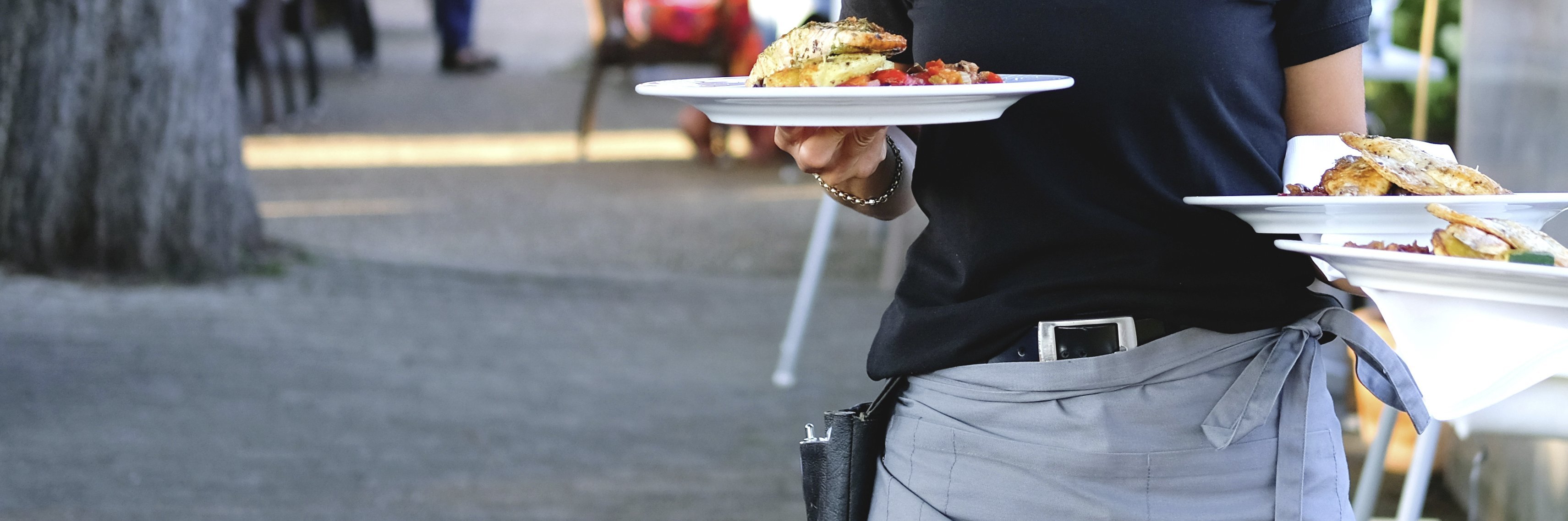 Eine Frau serviert in einem Restaurant Teller mit Essen.