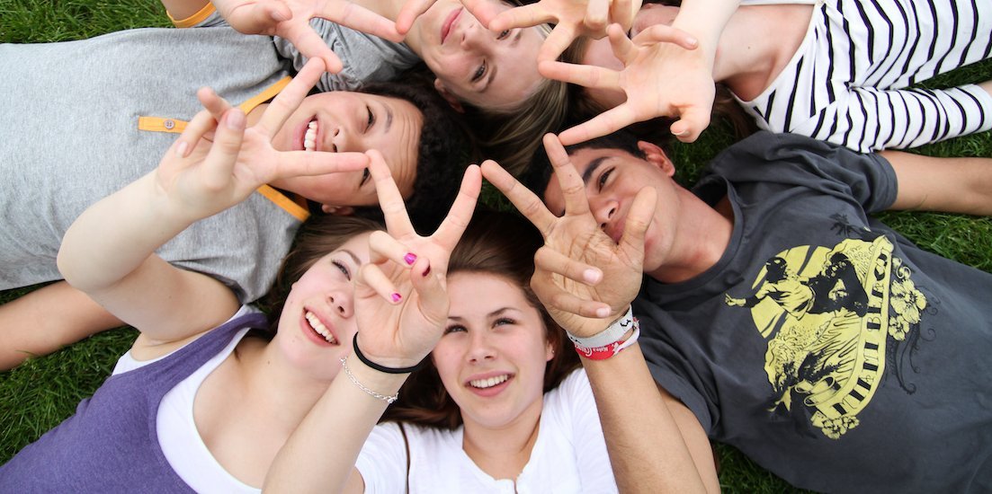 Sieben Jugendliche liegen im Kreis auf dem Rasen.. Artikel "Ganztag" öffnen.