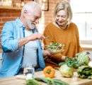 Älteres Paar in der Küche, Mann hält Schüssel mit Salat in der Hand