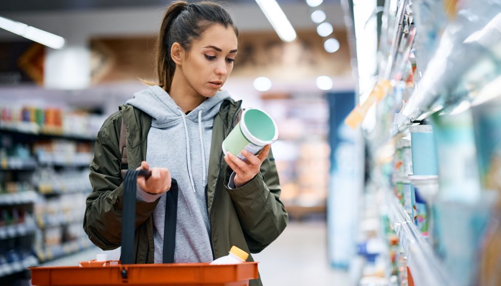 Frau schaut im Supermarkt auf Lebensmittelzutatenliste
